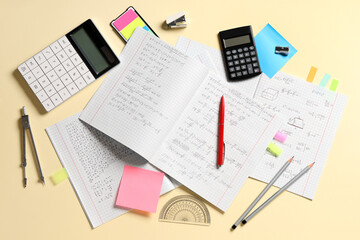 Obraz premium Copybooks with handwritten maths formulas and stationery on yellow background