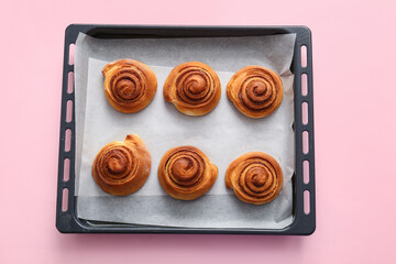 Baking dish with sweet cinnamon rolls on pink background