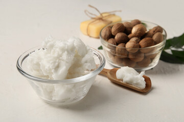 Glass bowl of shea butter with nuts and soap bar on white background