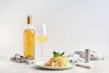 Plate with tasty pasta carbonara, bottle of wine and glass on table