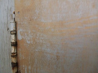 Rusty door hinges cut into the wooden door, connecting fasteners screwed in, construction parts.