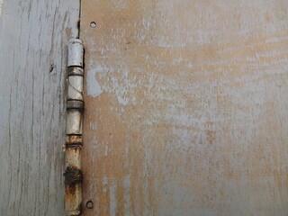 Rusty door hinges cut into the wooden door, connecting fasteners screwed in, construction parts.