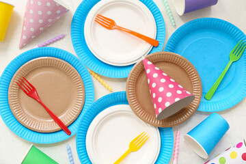Composition with paper disposable tableware and decor for birthday party on light background