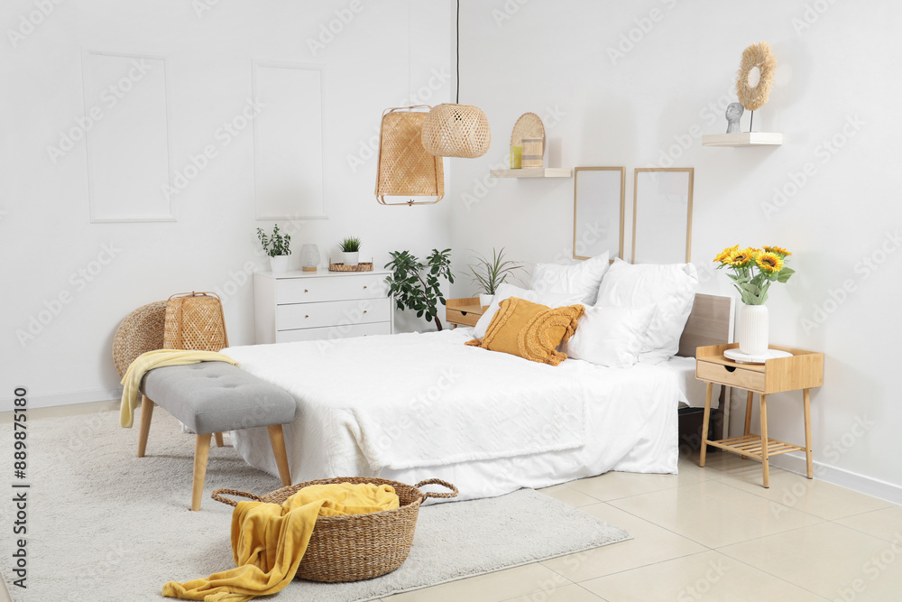 Poster interior of light bedroom with cozy bed and beautiful sunflowers on bedside table