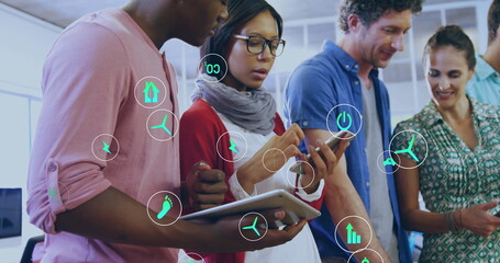 Image of ecology icons over diverse colleagues using tablet in office