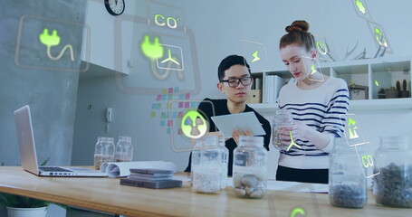 Image of ecology icons over diverse colleagues using tablet in office