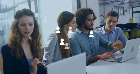 Image of media icons over diverse colleagues using laptop in office