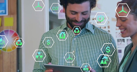 Image of ecology icons over diverse colleagues using tablet in office