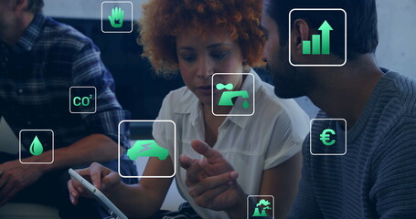 Image of ecology icons over diverse colleagues using tablet in office