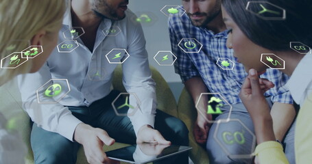 Image of ecology icons over diverse colleagues using tablet in office