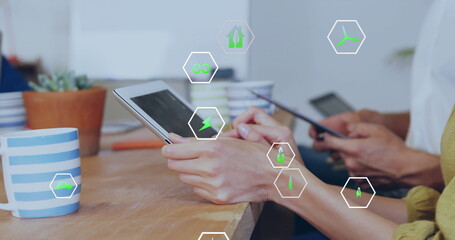 Image of ecology icons over diverse colleagues using tablet in office