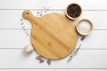 Cutting board and different spices on white wooden table, flat lay