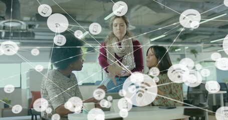 Image of network of connections with icons over diverse female colleagues using tablet in office