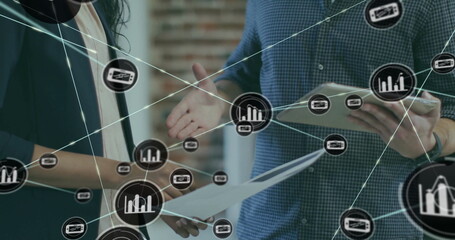 Image of network of connections with icons over diverse colleagues using tablet in office