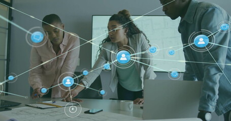 Image of network of connections with icons over diverse colleagues discussing work in office