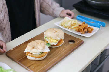 Woman Making Delicious Burgers With Vegetables, French Fries And Sausages At White Table, Top View