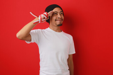 Young Indonesian man gives a salute gesture while celebrating Indonesian Independence Day on August...