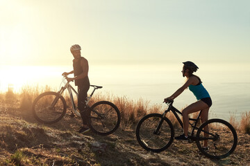 Fototapeta premium Bike, mountains and couple with fitness, nature and cardio with fitness, time together and routine. Hobby, healthy man and woman with cycling, challenge or endurance with training, workout and travel
