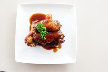 A close-up photo of a plate overflowing with Korean fried chicken wings. The wings are glazed in a glossy red sauce and sprinkled with white sesame seeds.