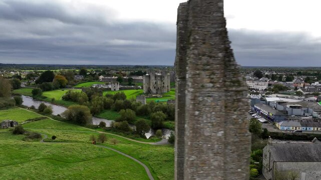 Trim Castle, County Meath, Ireland, October 2023. Drone orbits the Medieval Stronghold, passing crumbling ruins of St. Mary's Abbey revealing the town on the banks of the Boyne River.