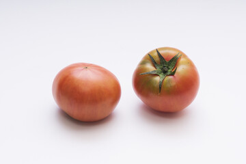 Close up of two raw tomato with red fruit and stalk on white floor, South Korea
