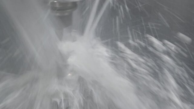 The 5-axis CNC milling machine  simultaneous cutting the automotive  part with liquid coolant method.