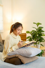 Young woman sitting and reading a book from the couch.