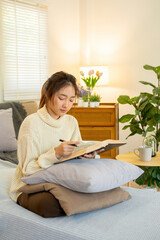 Young woman sitting and reading a book from the couch.