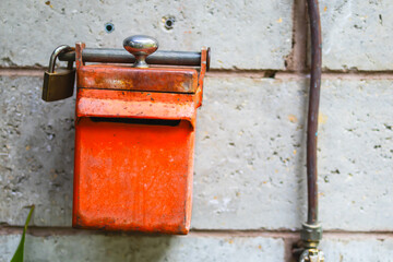 A vintage of red rusty view metal box, post box or bill box with key looking lock on concrete wall background.