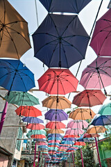 colorful umbrellas are hanged from the top to cover the way as a decoration