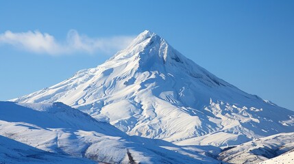 A snow-covered mountain peak against a clear blue sky, with the surrounding landscape blanketed in white