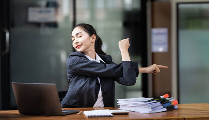 Relaxed office worker woman stretching hands and body taking break from work