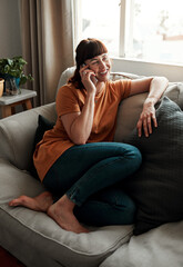 Obraz premium Woman, phone call and happy on couch for chat, mobile app and relax in morning or living room. Networking, technology and person in home for discussion, social media and online for news or gossip