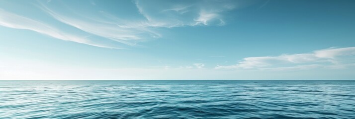 The vast expanse of the ocean stretches out before a clear blue sky dotted with wispy white clouds