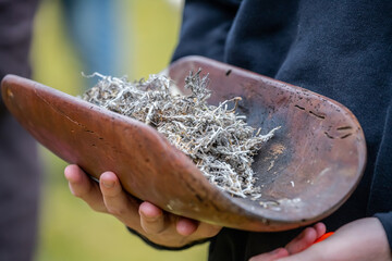 Australian Aboriginal smoking ceremony, human hands hold ritual dish at indigenous community event, joining to culture
