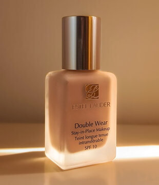 estee lauder double wear foundation bottle with copy space in warm sunlight, luxury high end makeup packaging closeup, editorial