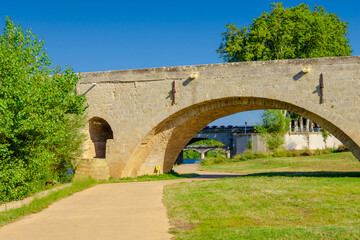 Fototapeta premium Pont Vieux- A bridge spans a river with a castle in the background