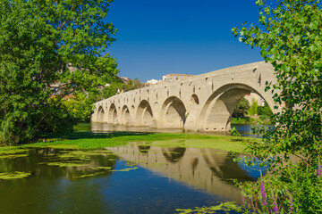 Fototapeta premium Pont Vieux- A bridge spans a river with a castle in the background