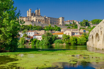 Fototapeta premium Cathedral Saint-Nazaire-A river runs through a town with a castle in the background