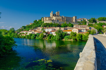 Obraz premium Cathedral Saint-Nazaire-A river runs through a town with a castle in the background