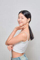 Asian female cosmetics model touching her skin with a confident expression.