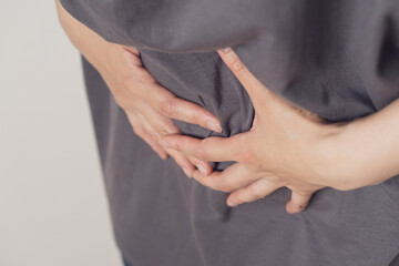 腹痛でお腹を押さえる女性