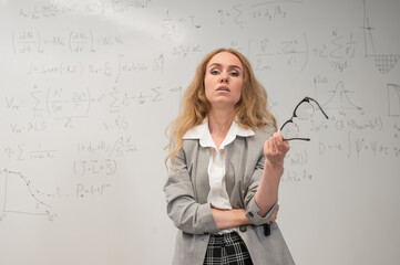Fototapeta premium A Caucasian woman stands at a blackboard with written formulas.