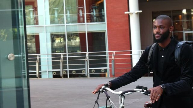 Closeup of African businessman walking alongside his electric bicycle on the way to office