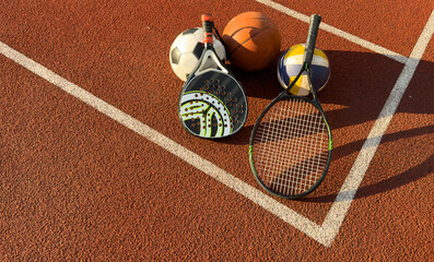 A variety of sports equipment including an american football, a soccer ball, a tennis racket, a tennis ball, and a basketball