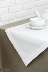 Beige Tablecloth on White Brick Wall With Teacups and Teapot