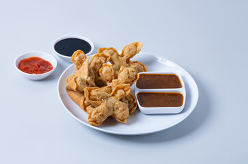 Batagor,(Fried Tofu Meatballs), served on a serving plate with peanut sauce, sambal, and chili sauce. This is authentic street food from Bandung Indonesia. Perfect for recipes, articles or any cooking