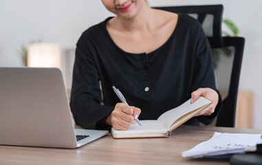 Young Accountant Working on Financial Documents at Home with Laptop and Notebook, Focused on Budgeting and Planning