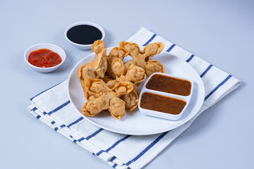 Batagor,(Fried Tofu Meatballs), served on a serving plate with peanut sauce, sambal, and chili sauce. This is authentic street food from Bandung Indonesia. Perfect for recipes, articles or any cooking