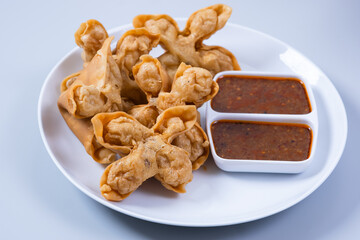 Batagor,(Fried Tofu Meatballs), served on a serving plate with peanut sauce, sambal, and chili sauce. This is authentic street food from Bandung Indonesia. Perfect for recipes, articles or any cooking